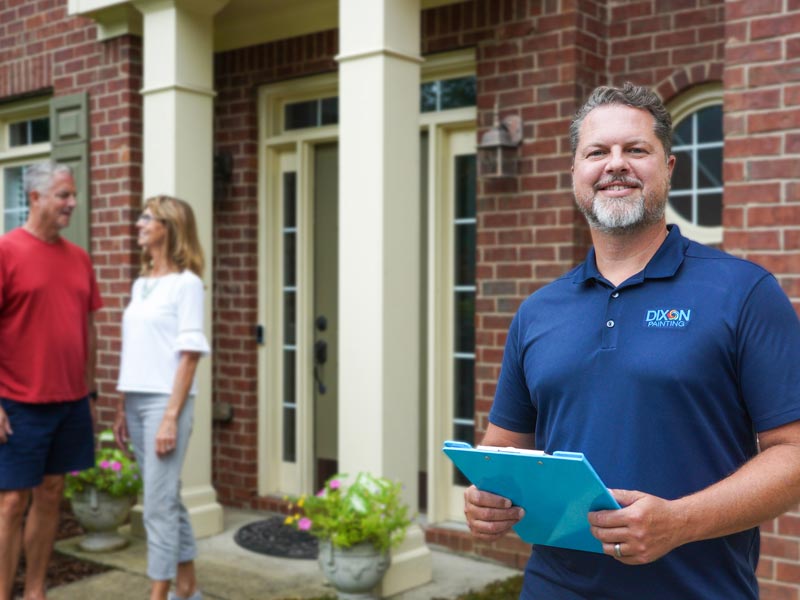 smiling Dixon Painting team member standing outside brick home in Marietta, GA