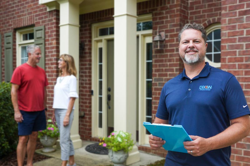 smiling Dixon Painting team member standing outside brick home in Marietta, GA