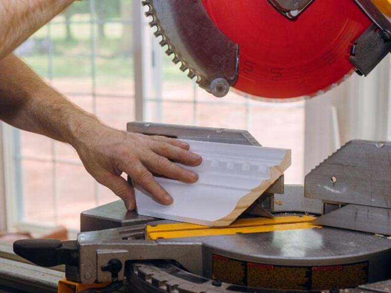 man cutting crown molding with saw