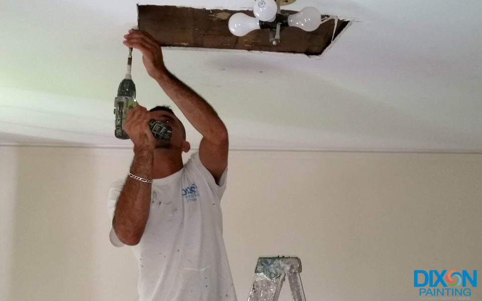 A man using a drill to work on a ceiling