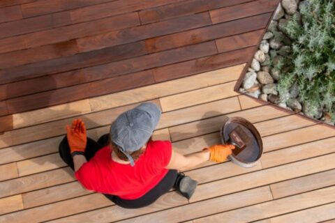 Painter staining a wooden deck- Dixon Painting