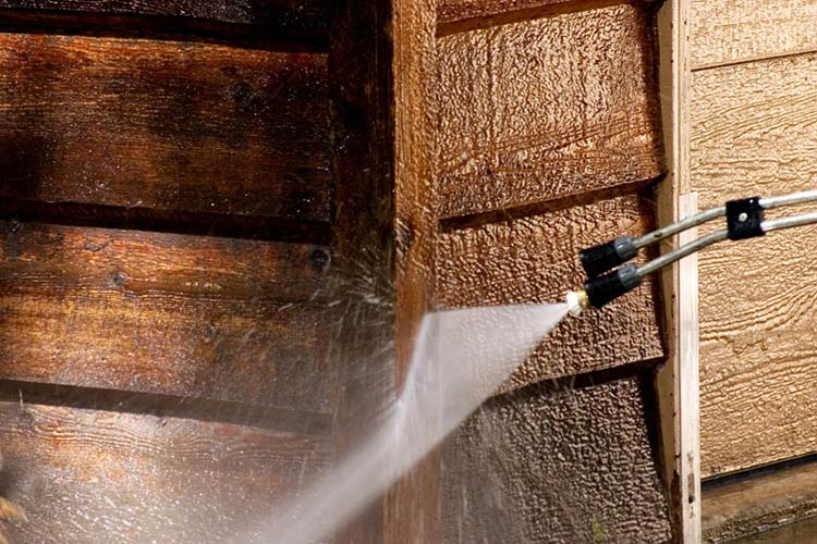 A man sprays water onto a wooden wall