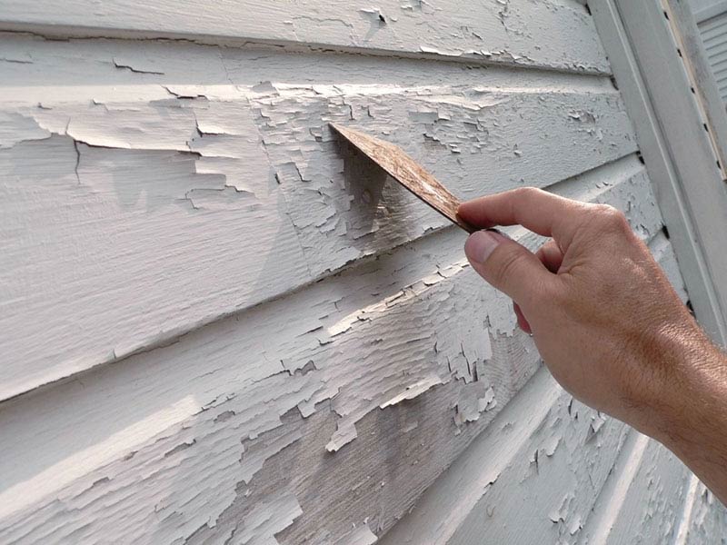 A person removing paint from the wall